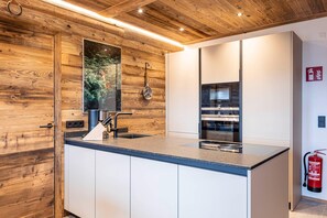 A modern kitchen with wooden paneling, a large island with a sink, and built-in appliances.