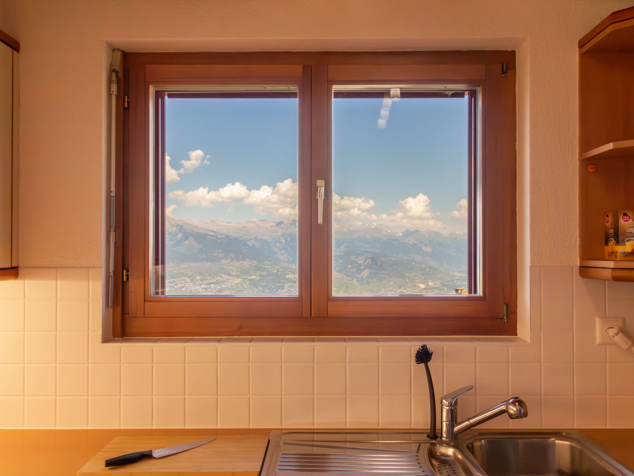 A kitchen with a window overlooking a mountainous landscape.