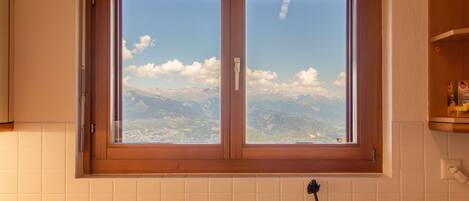 A kitchen with a window overlooking a mountainous landscape.