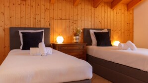Ein Zimmer mit zwei Betten, Holzwänden, einem Nachttisch mit Lampe und einem Blumentopf.