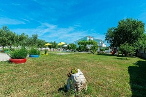 Guests can enjoy a serene outdoor space with a lush lawn, potted plants, and a natural rock feature.
