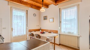 A cozy kitchen with a wooden ceiling, a dining table with chairs, a clock, and a radiator. - Vento Alpino by Interhome (Valle di Non)