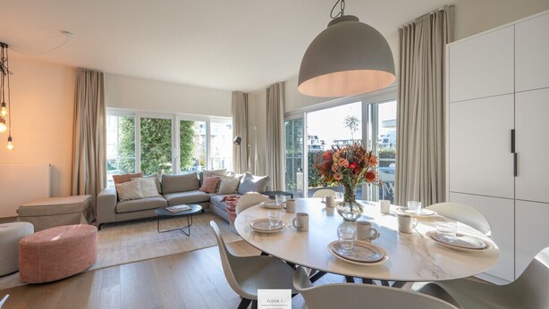 Un salon moderne avec une table à manger ronde, un canapé et une grande fenêtre.