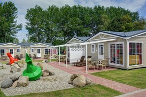 Cozy cabins with covered outdoor seating areas and large windows.