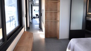 Un dormitorio moderno con un ventanal grande, un banco de madera y una cama con colcha estampada.