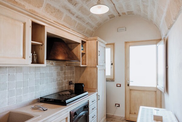 A compact kitchen with a built-in oven, a stovetop, and wooden cabinets.