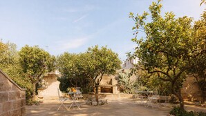An outdoor patio with stone walls, a seating area with metal chairs, and a stone fireplace. - terrance apartment - air conditioning | 5 minute sea | - VinTage Malvasia (Diso)