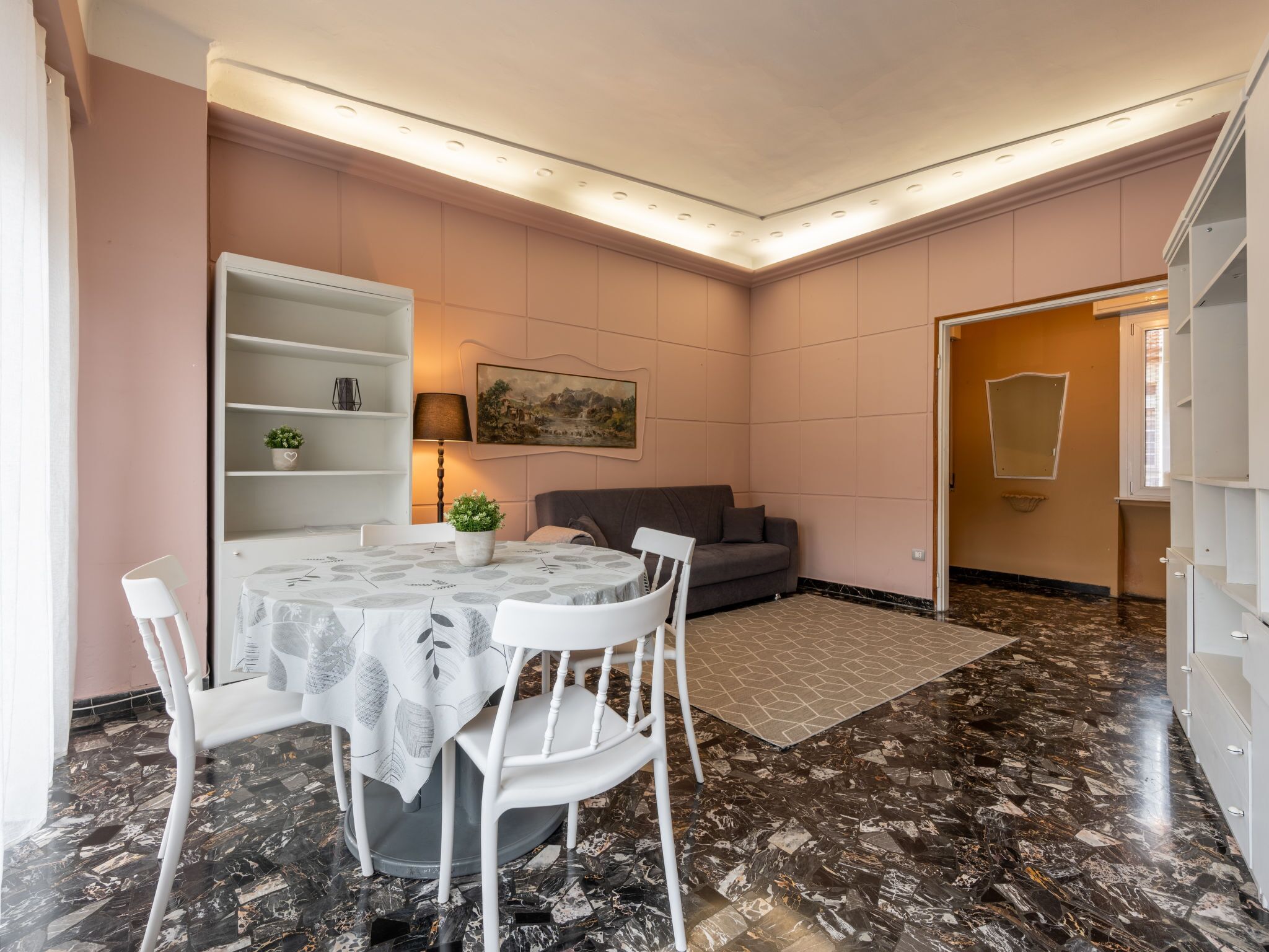 Een moderne woonkamer met een eethoek, met een marmeren vloer, een bank, een tafel met stoelen en een boekenkast.