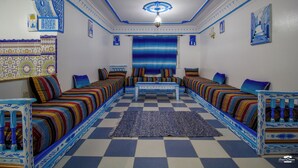 Een kamer met een geruit vloerkleed, behang met patroon en blauw-witte decoratie.