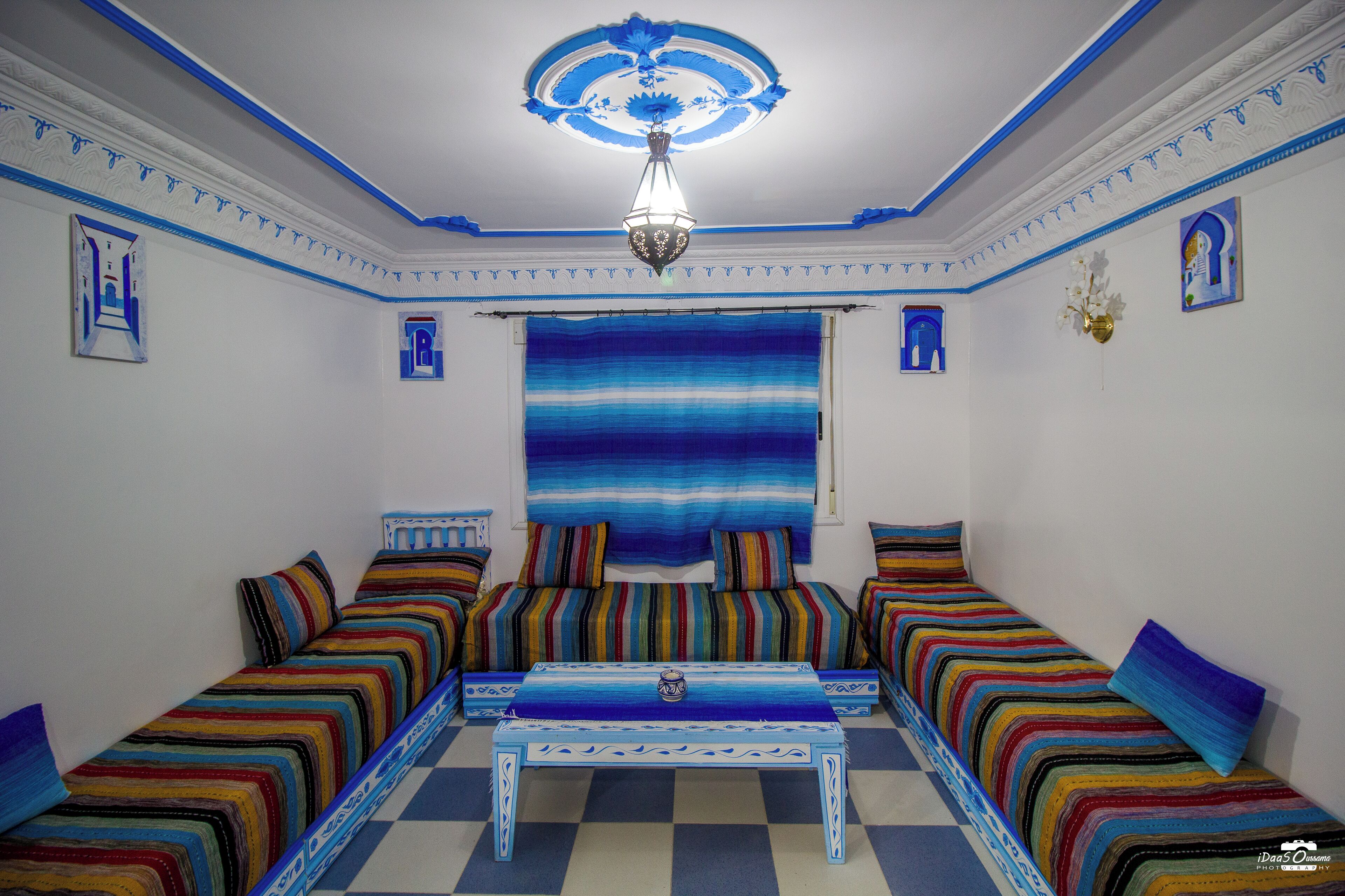 Een kamer met een geruite vloer, een centrale tafel en gestreepte banken.