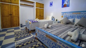 Een slaapkamer met twee bedden, houten kasten, een geruit vloertapijt en een blauw-witte bedsprei.
