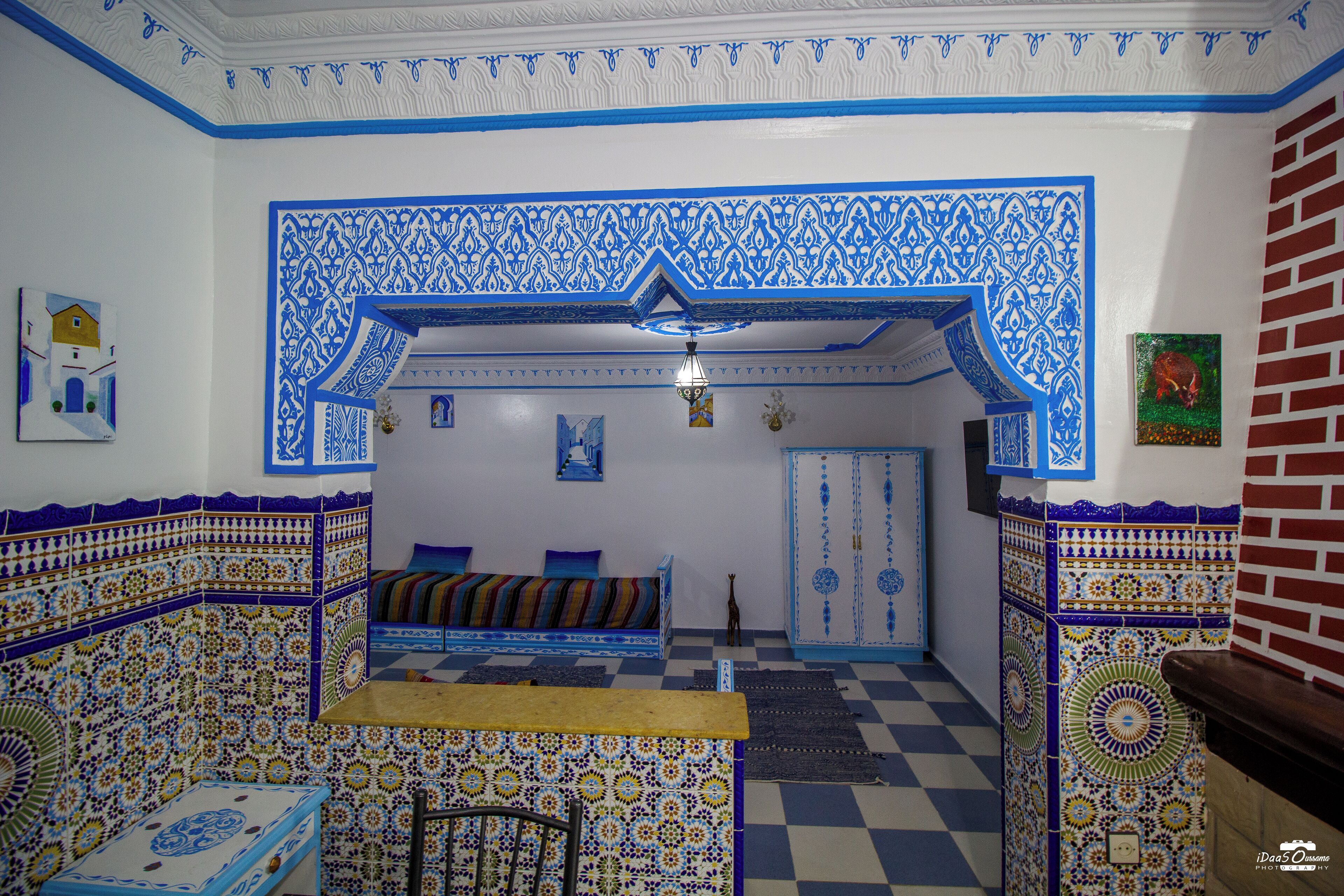 A room with a checkered floor, patterned walls, a sofa, and a small table.