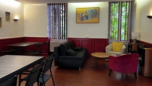 A room with a dining table, chairs, a sofa, a small round table, and a television. - 15-person gite with 6 bedrooms and bar area ideal for family reunions! (Varzy)