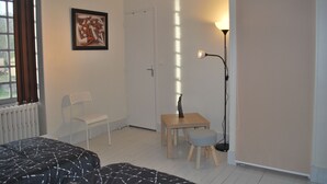 A bedroom with a bed, a chair, a desk, a lamp, and a door. - 15-person gite with 6 bedrooms and bar area ideal for family reunions! (Varzy)