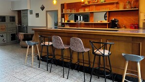A bar area with wooden bar stools, a coffee machine, and shelves with glassware and bottles. - 15-person gite with 6 bedrooms and bar area ideal for family reunions! (Varzy)