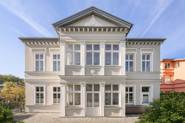 A two-story building with a symmetrical facade, large windows, and a central entrance with a decorative pediment. - Villa Luise 07 - Luxury top-floor apartment with a sauna and balcony (Heringsdorf (Seebad))