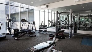 Ein modernes Fitnessstudio mit Laufbändern, Hanteln und einer Spiegelwand.