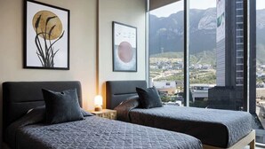 Une chambre d’hôtel avec deux lits, une grande fenêtre donnant sur les montagnes et des œuvres d’art accrochées aux murs.