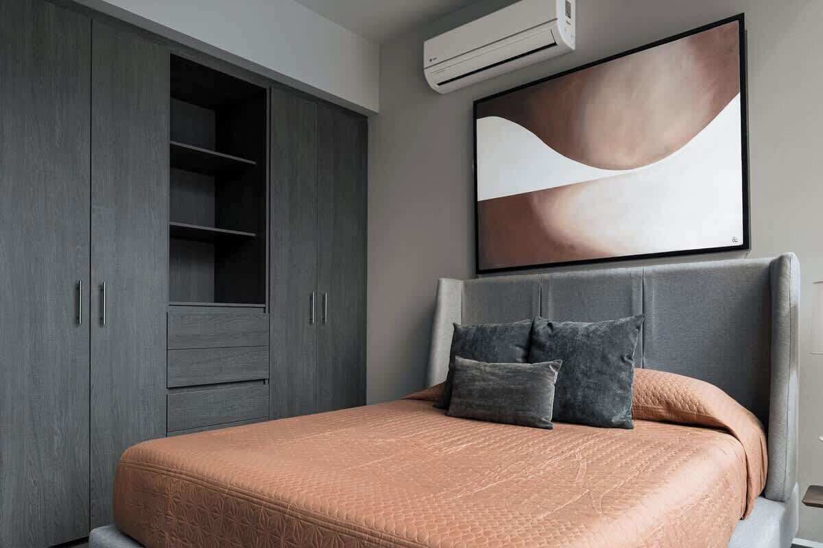 A bedroom with a bed, grey wardrobe, and a large abstract painting on the wall.