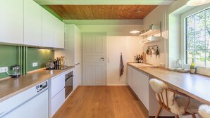 Eine moderne Küche mit Holzböden, weißen Schränken und einem Fenster, das für natürliches Licht sorgt.