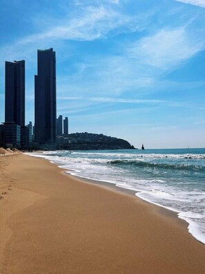 A beach with a sandy shore and ocean waves.