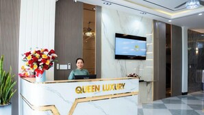 Un comptoir d’accueil au design en marbre, sur lequel le nom « QUEEN LUXURY » est clairement affiché.