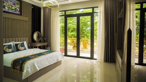 Une chambre moderne avec un grand lit, un miroir, un tableau et un balcon doté d’une rambarde jaune.