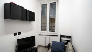 Un dormitorio pequeño y moderno con cama, televisor, armario y ventana con persianas.