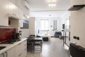 Een moderne keuken met een gasfornuis, witte kasten en een eethoek met een tafel en stoelen.