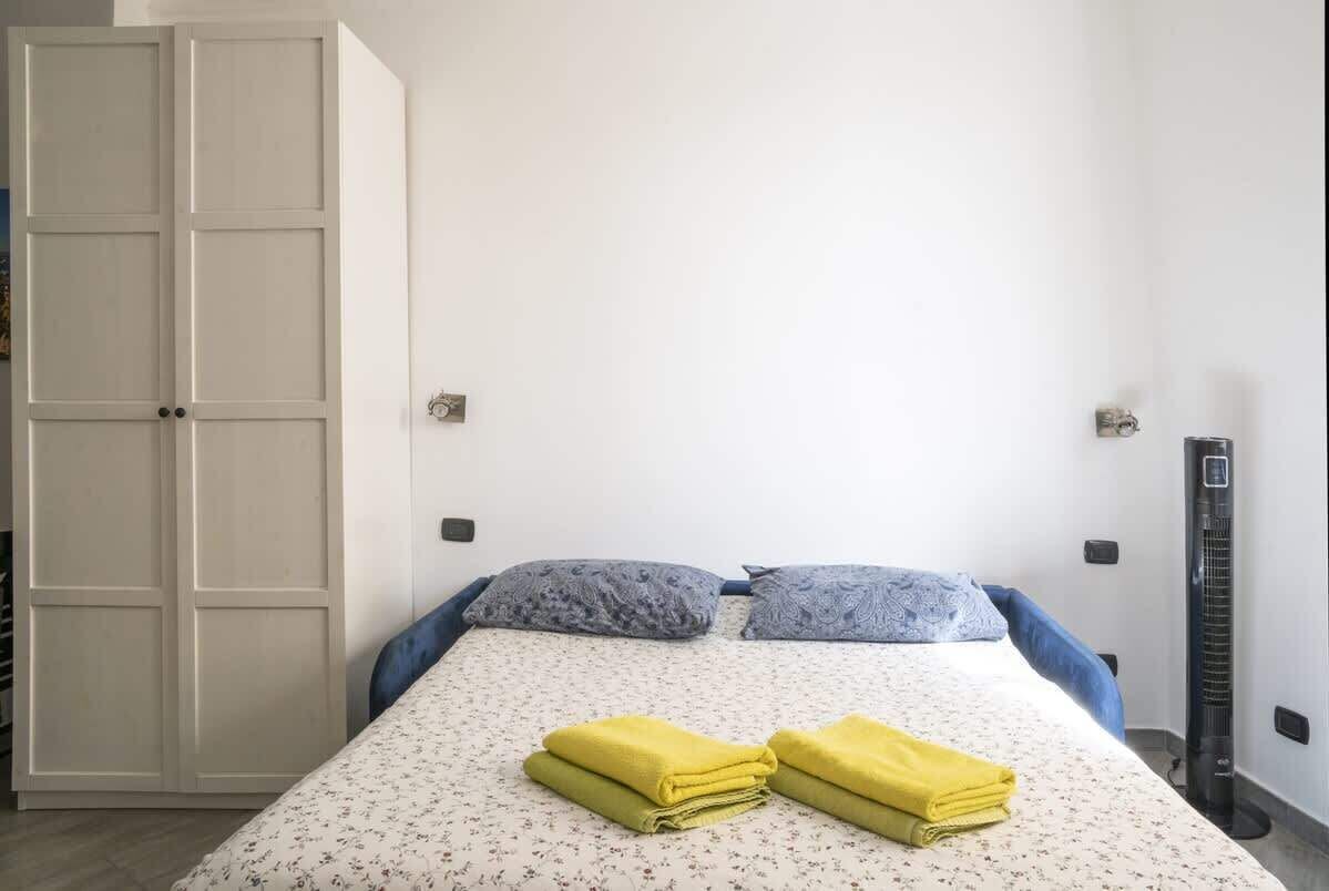 Une chambre à coucher avec un lit, deux oreillers, un radiateur et une armoire.