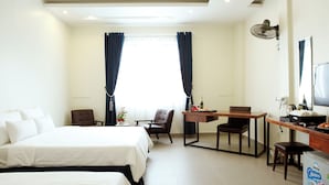 Et hotelværelse med to senge, et skrivebord med stol, et fjernsyn og en minibar.