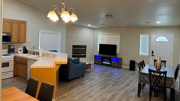 A modern kitchen with wooden cabinets, a built-in oven, and a dining area with a wooden table and chairs.