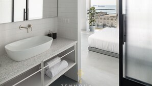 A modern bathroom with a large sink, a mirror, and a view of the city through a large window. - Nero Luxury Suites by Zennova (Thessaloniki)