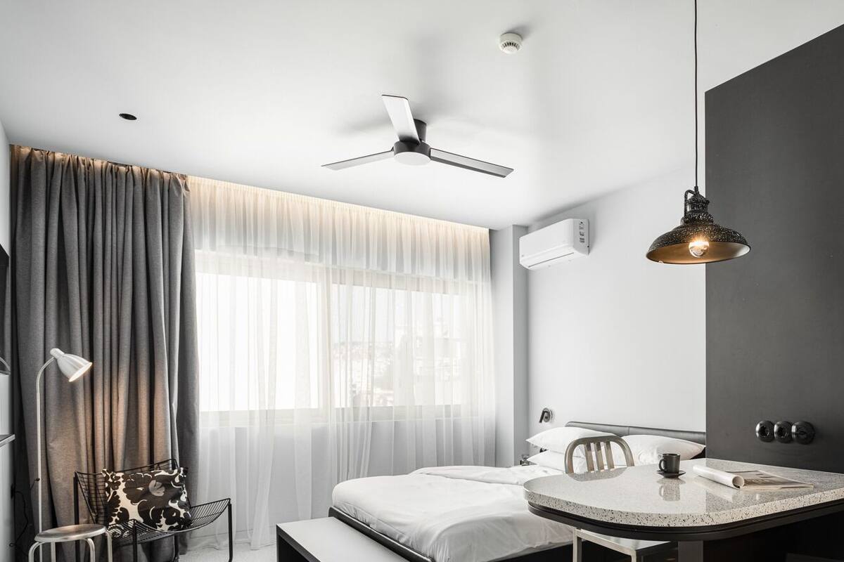 Una habitación de hotel moderna con una cama, una mesita de noche y un escritorio con una silla.
