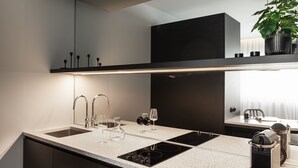 A modern kitchen with a large island, built-in oven, and a microwave. - Nero Luxury Suites by Zennova (Thessaloniki)