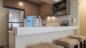 Een moderne keuken met een ingebouwde LG-koelkast, een welkomstbord, twee waterflessen en een koffiezetapparaat. Er staan drie barkrukken bij de bar.