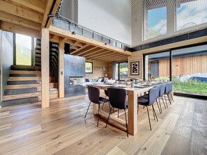 A modern kitchen with a large island, wooden beams, and a view of the outdoors. - Chalet Béli - Montriond - Centre village (Montriond)