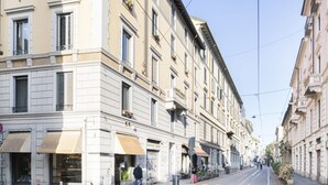 A street with buildings, awnings, and a clear sky. - Easylife - A touch of design in Porta Venezia (Milano)