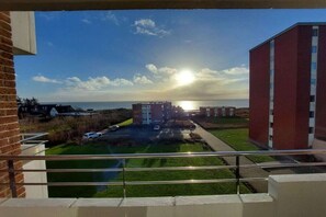 A view from a balcony overlooking a building complex with a clear sky and the sun setting or rising.