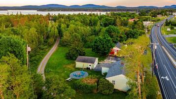 Surrounded by lush greenery and a serene body of water, this property offers a peaceful retreat with easy access to the road.