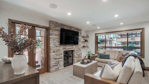 Una sala de estar con chimenea de piedra, un televisor de pantalla plana, un sofá y una mesa de centro.
