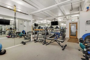 A gym with various exercise equipment, mirrors, and a television.