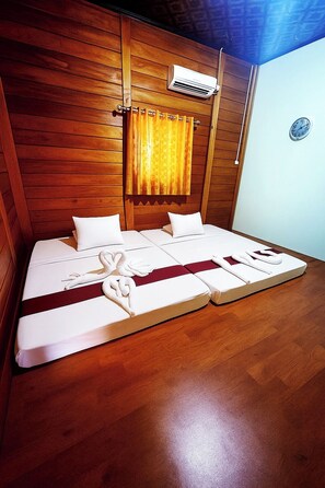 Ein Zimmer mit Holzwänden, einem Bett, einer Klimaanlage und einer Wanduhr.