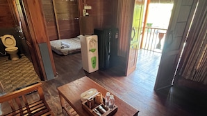 A wooden interior with a wooden table, a bench, a refrigerator, and a bed. - Pondok Cilega (Mandirancan)