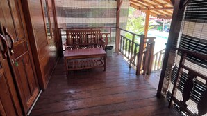 A wooden porch with a bench, wooden railings, and a view of a pool area. - Pondok Cilega (Mandirancan)