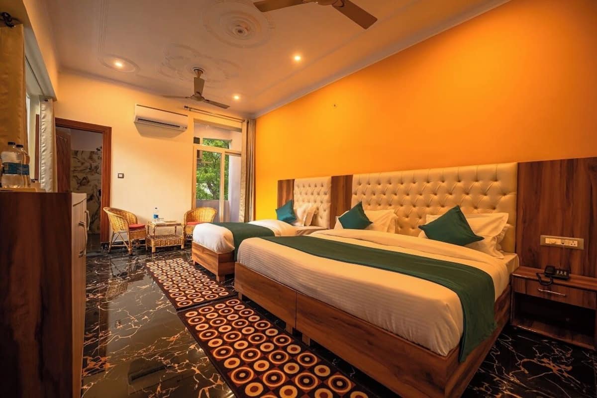 Habitación de hotel con dos camas, cabecera de madera, suelo de mármol y ventilador de techo.