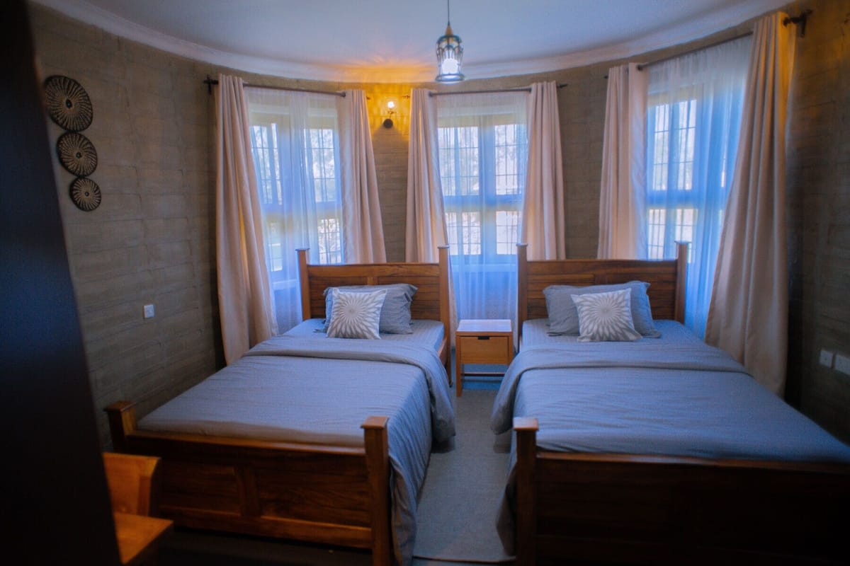 A room with two wooden beds, a small table, and a hanging light fixture.