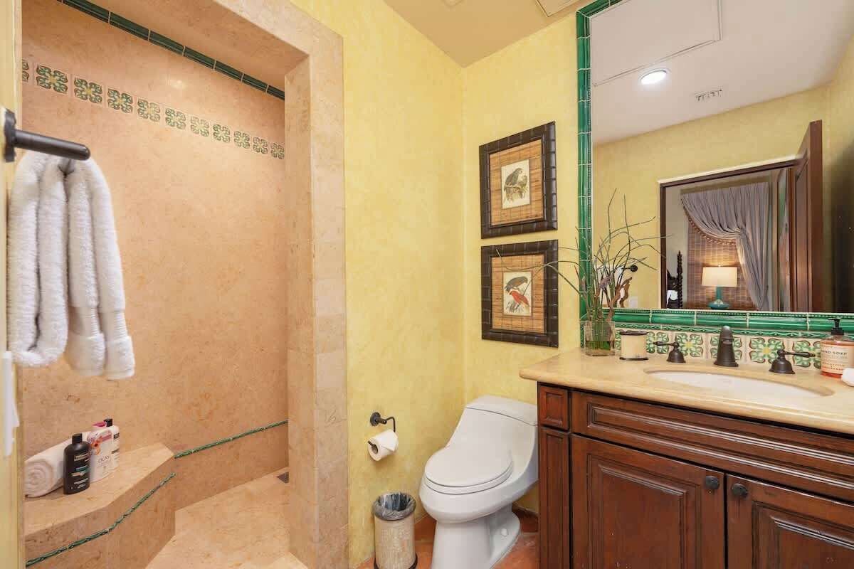 Un baño con ducha, inodoro y tocador con espejo.