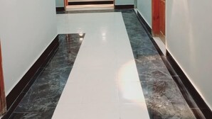 Un pasillo con un ventilador de techo, una lámpara y una puerta de marco de madera.
