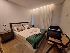 Une chambre à coucher moderne avec un lit, des tables de chevet, un bureau et une chaise.